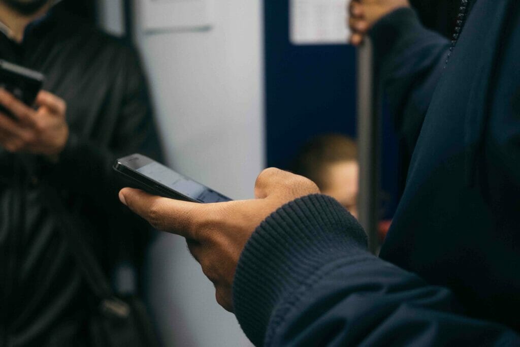 Man in sweathirt and in a train holding his phone